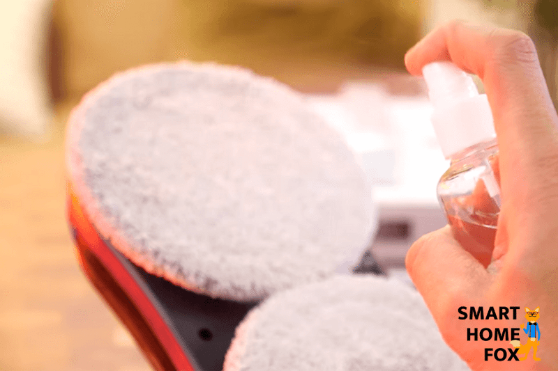 Моющее средство распыляется на салфетку робота для мойки окон.